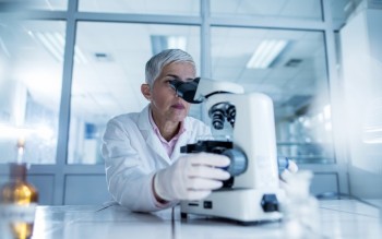 Mature scientist looking through a microscope in a laboratory.
